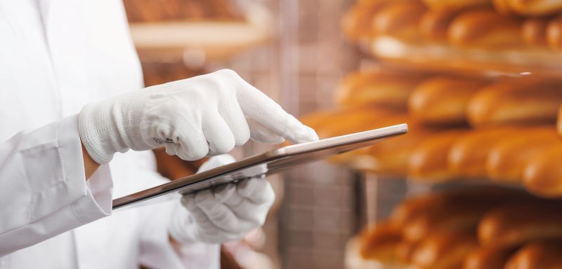 bread in background, white glove pointing to an ipad