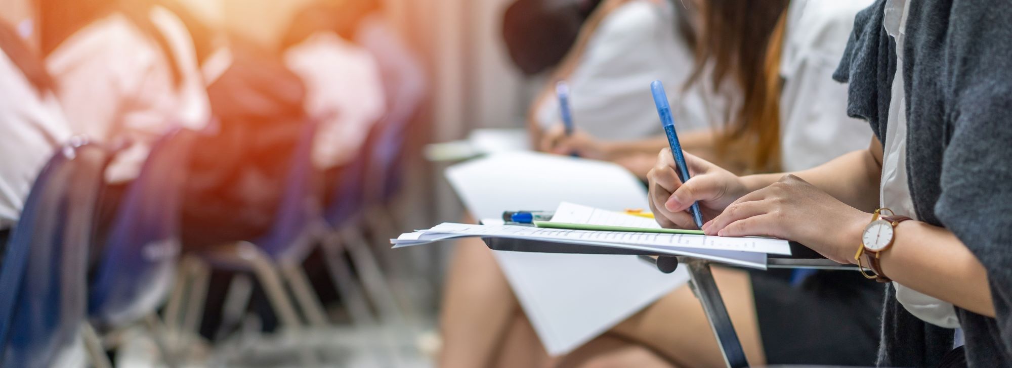 female sat at a desk writing on exam paper