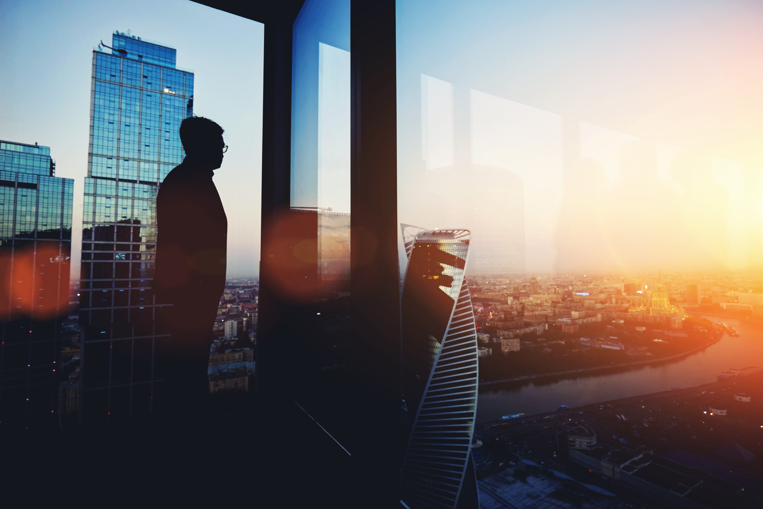 Man looking out of a glass window in a tall building